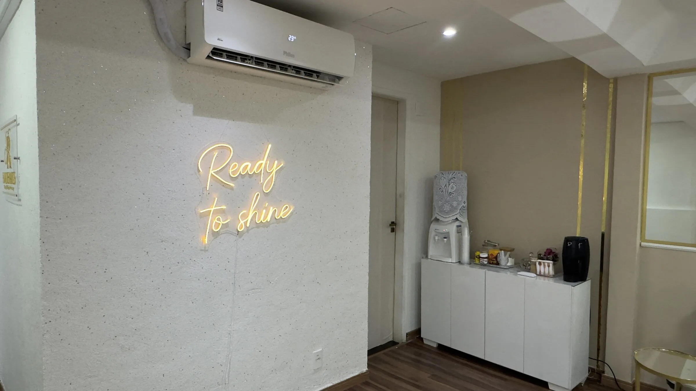 Letreiro em neon dourado com a frase Ready to shine na parede do estúdio
