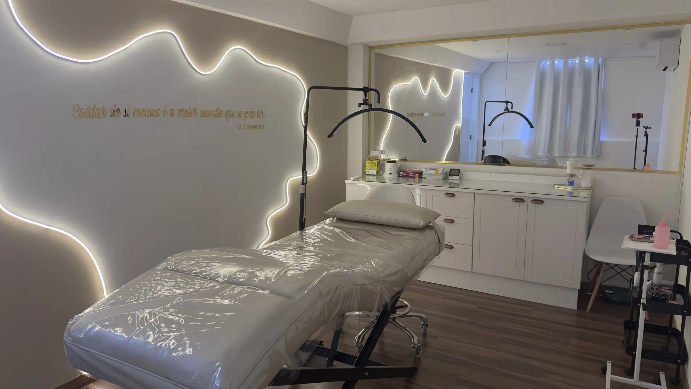 Sala de atendimento, com maca, bancada e iluminação em LED contornando a parede